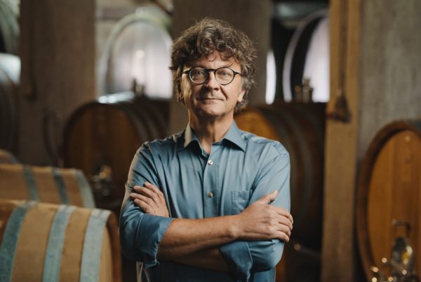 Defiant winemaker standing in front of barrels.